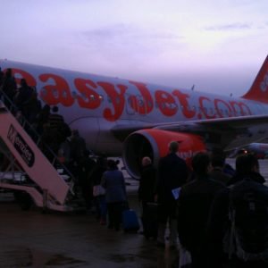 People queued on the hard standing waiting to board the plane in a twilight state. 